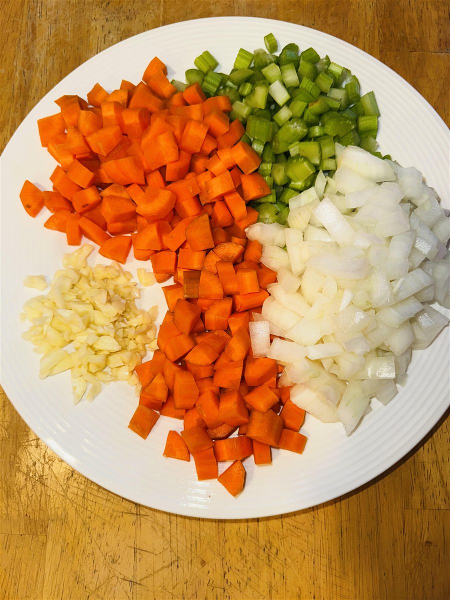 Diced carrots, celery and onion with minced garlic on a white plate