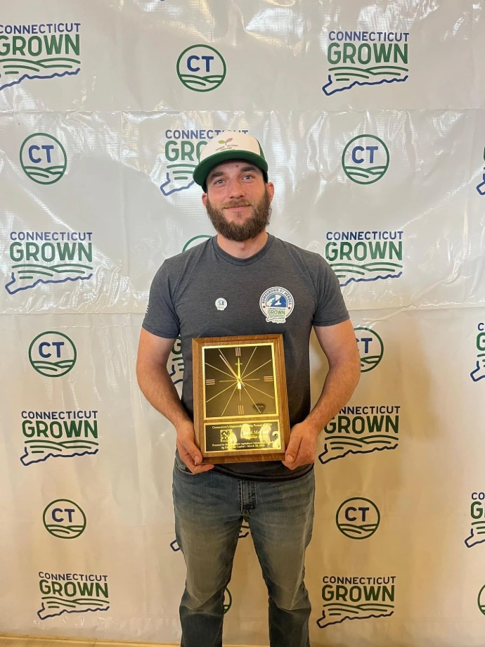 Steadfast Farms award winner holding plaque at Connecticut agriculture event